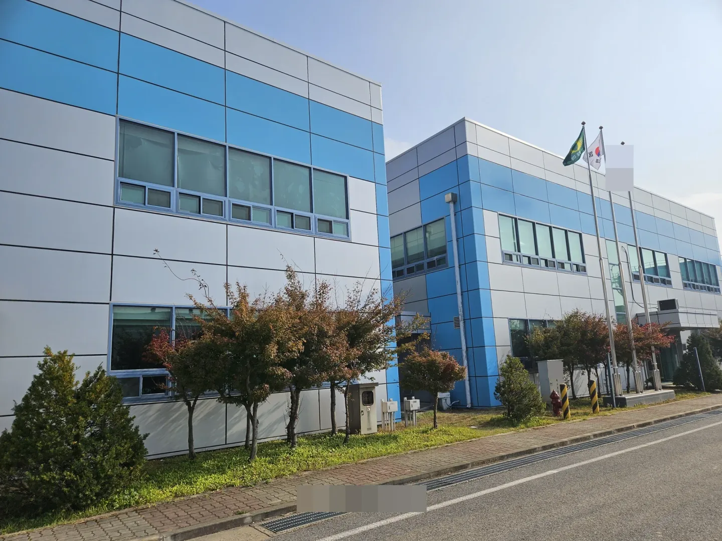 청소 후 도로 쪽에서 촬영한 파란색과 회색 패널 건물의 외관